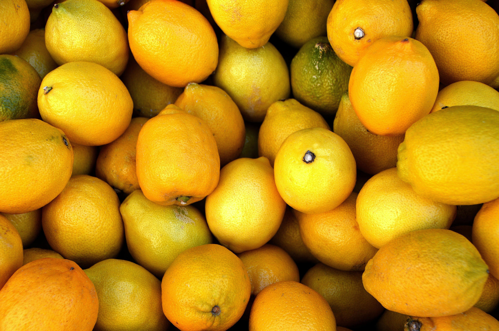 Stack of lemons and limes with a focus on yellow fruits.